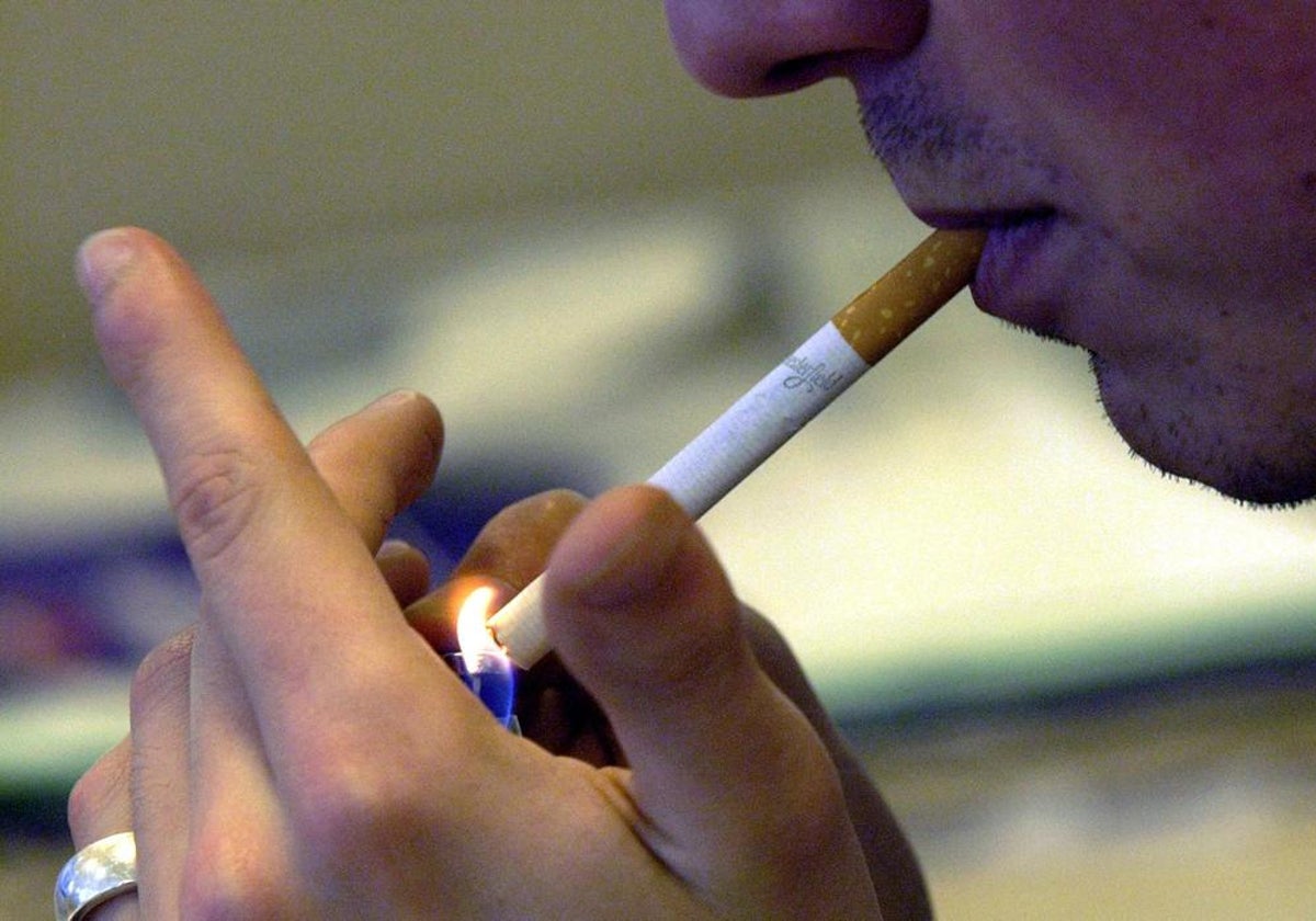 Un hombre enciende un cigarro