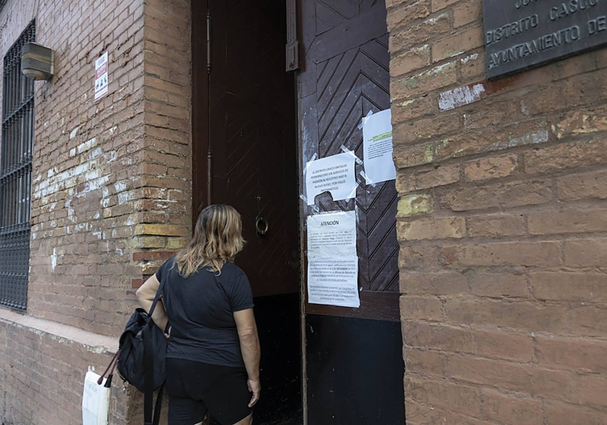 Una usuaria en la oficina del distrito Casco Antiguo en Sevilla, con la puerta llena de carteles