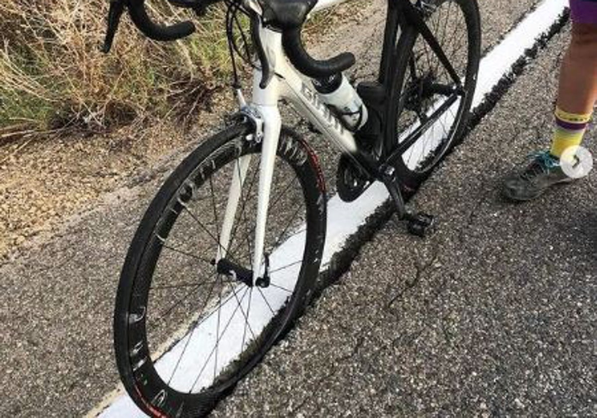 Una bicicleta con las ruedas metidas en el socavón de la carretera y sin arcén