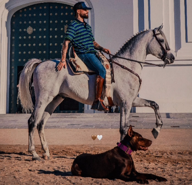 Maluma montando a caballo, posando delante de la ermita de El Rocío con su perro