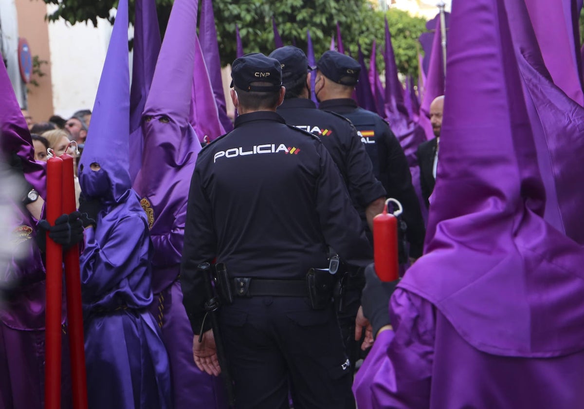 Agentes de la Policía Nacional cruzan el cortejo de la hermandad de la O