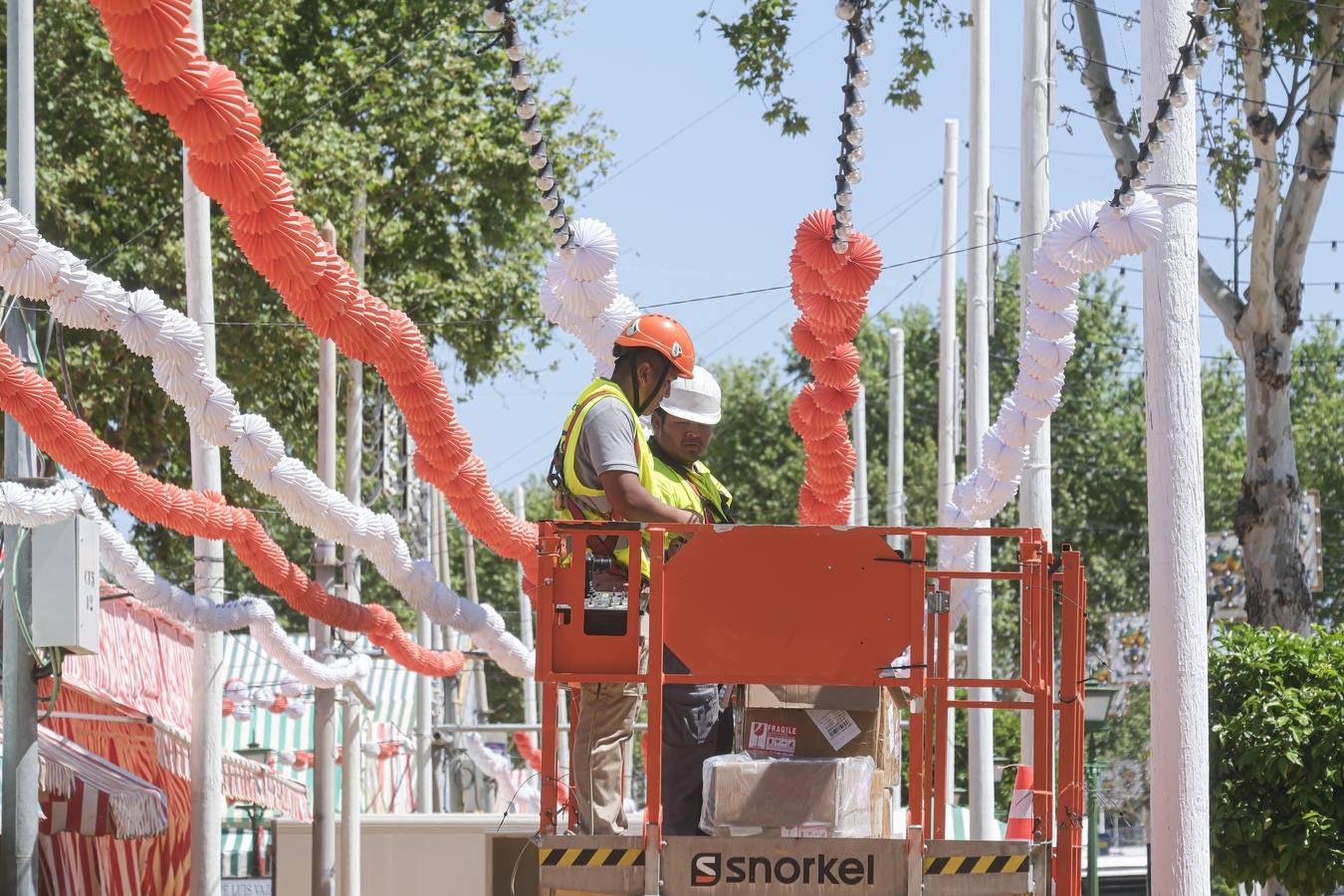 Operarios colocan los farolillos que se estropearon durante la lluvia de esta semana