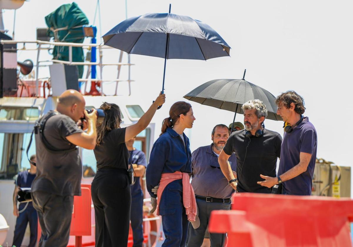 Alberto Rodríguez y Paco Baños hablan con Bárbara Lennie en el rodaje en el puerto de Huelva de 'Los tigres'. Detrás, el actor Joaquín Núñez