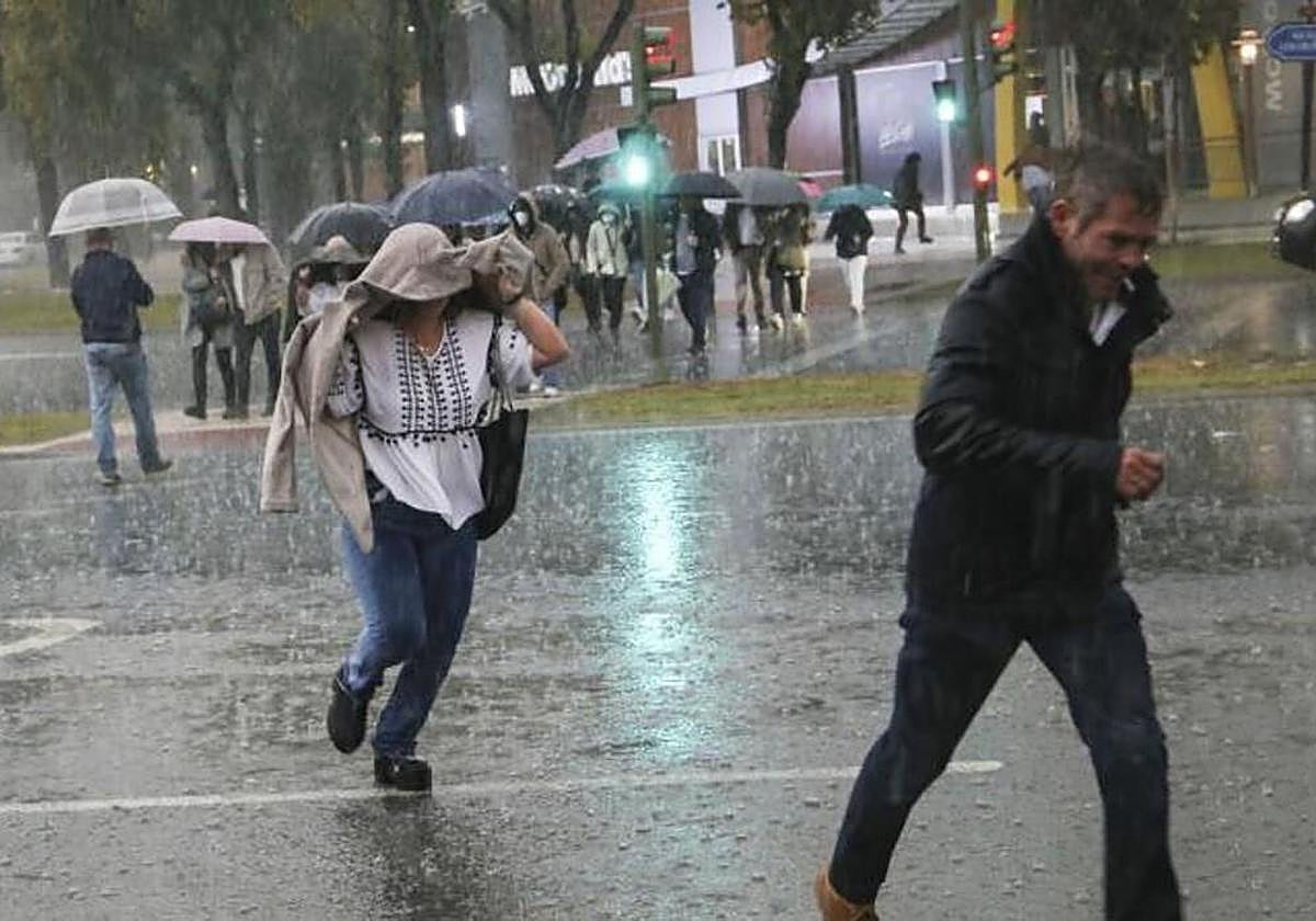 Personas huyendo de la lluvia en Sevilla