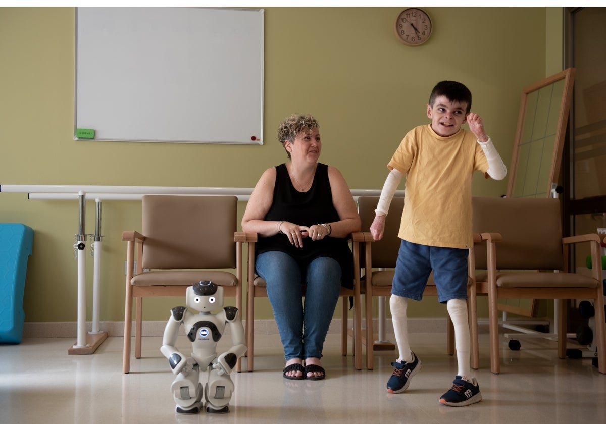 Leo con su madre, Lidia, y el robot Juande con el que hace terapia en el Hospital de San Juan de Dios de Sevilla