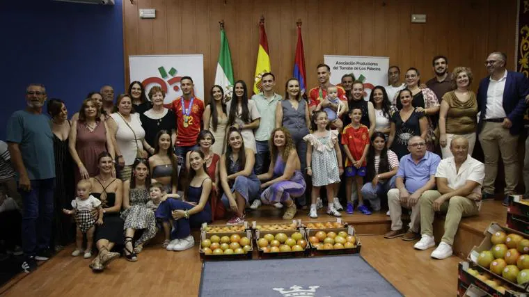 Navas and Fabian pose with their families and kilos of tomatoes at the town hall.