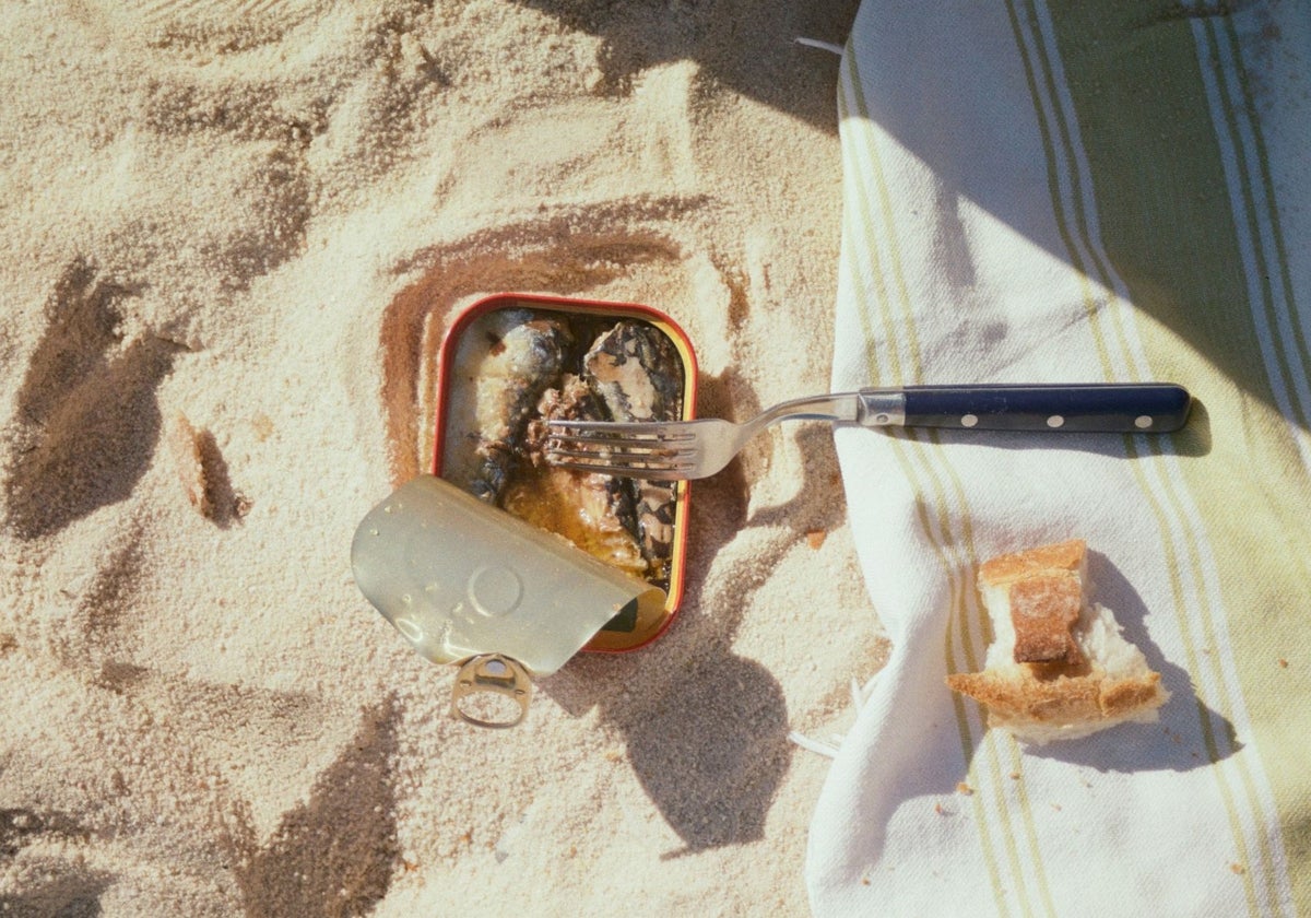 Una lata de conserva de sardinas acompañada de un trozo de pan