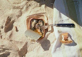 Una lata de conserva de sardinas acompañada de un trozo de pan