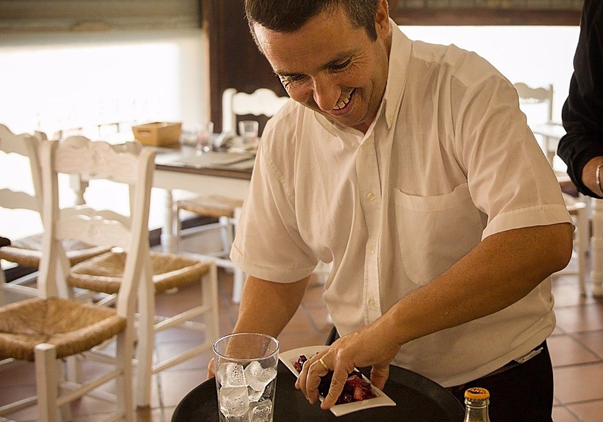 Un camarero con discapacidad intelectual atendiendo a una mesa del mesón 'Campeones' del barrio sevillano de Nervión