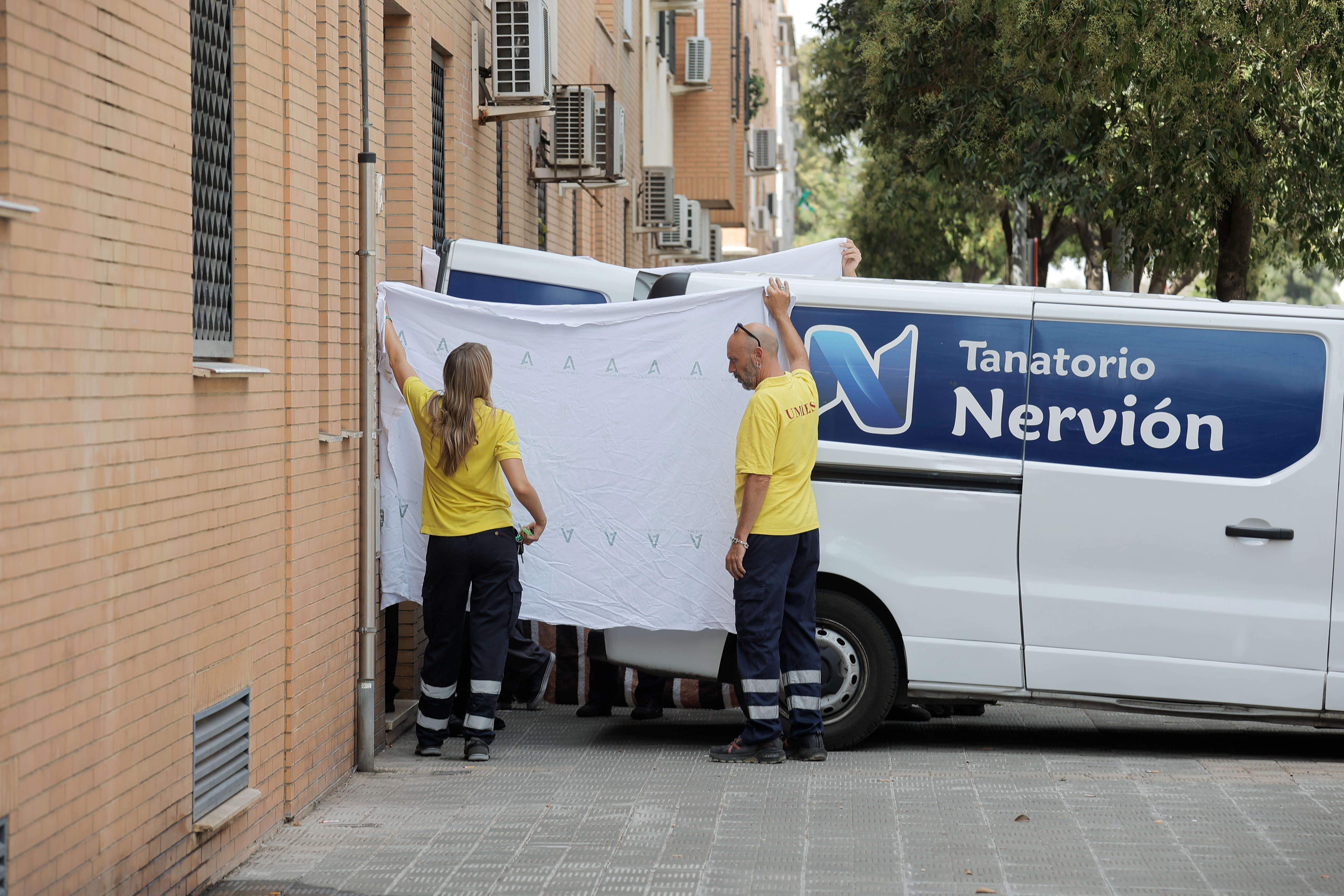 Personal de la unidad de asistentes sociales del Ayuntamiento tapan con sábanas la salida del féretro