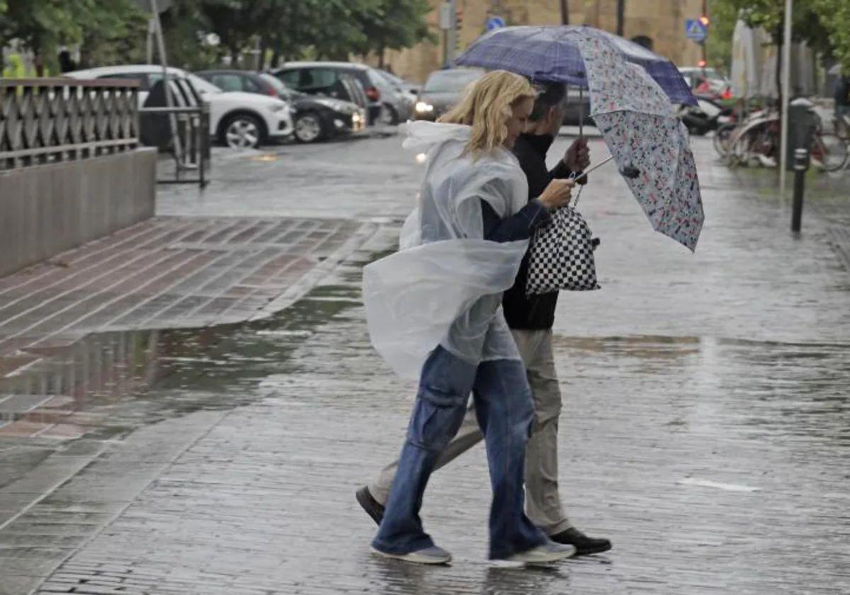 Personas caminando con paraguas bajo la lluvia en Sevilla