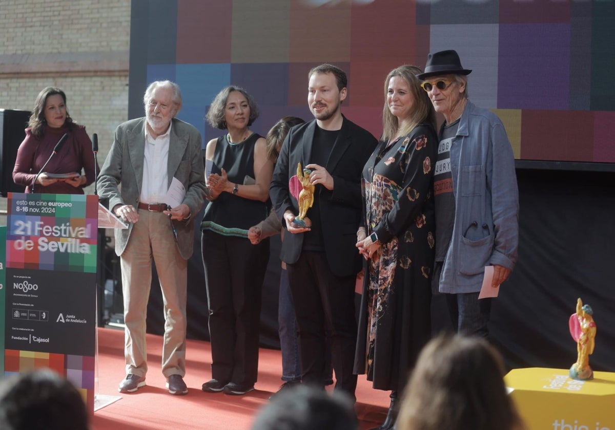 Gints Zilbalodis junto a Angie Moreno, delegada de Turismo y Cultura del Ayuntamiento de Sevilla, y miembros del jurado de la Sección Oficial, como Jeremy Irons o David Puttnam