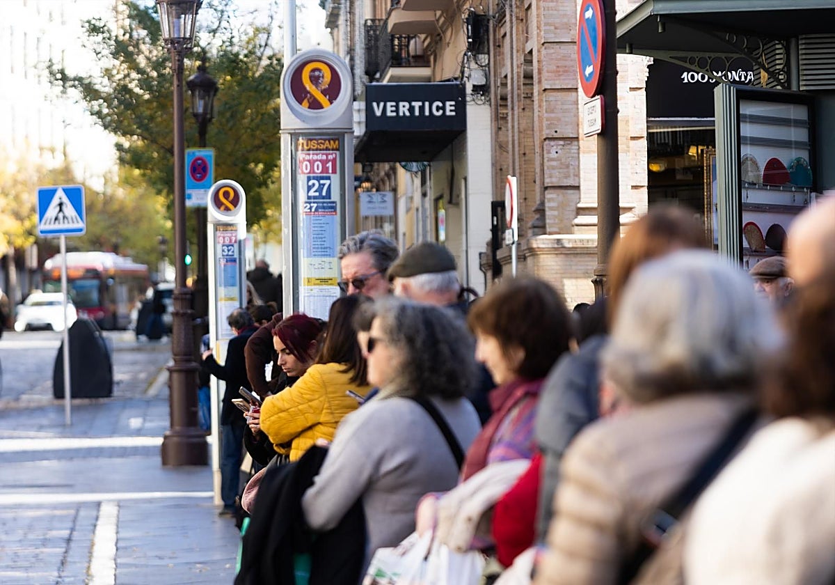 Pasajeros esperando en la parada del 27 en la Campana estas Navidades