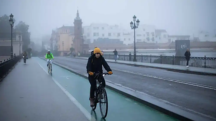 Una jornada de frío en Sevilla, con personas cruzando el Puente de Triana por la mañana