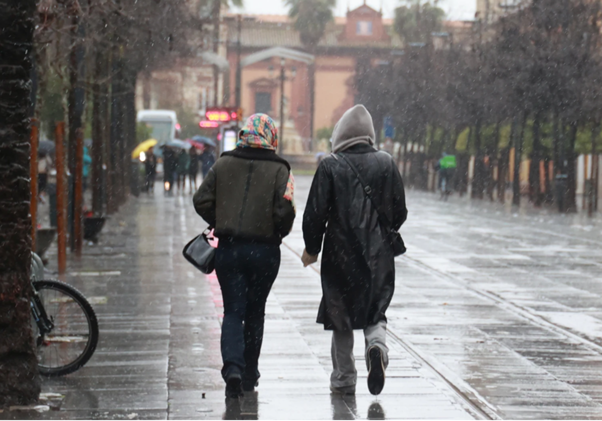 Dos personas caminan bajo la lluvia por la calle San Fernando