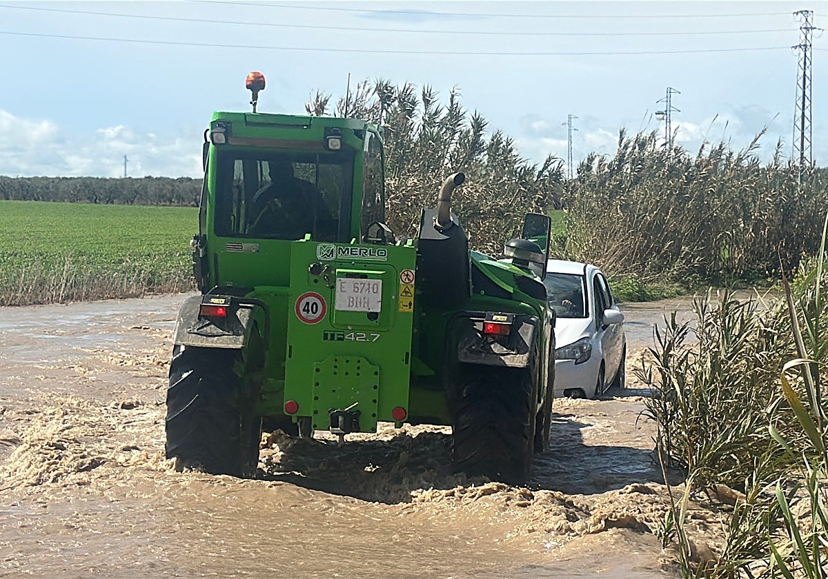 Dos vecinos con un tractor con brazo extensible consiguen llegar hasta el coche y rescatar al hombre mayor