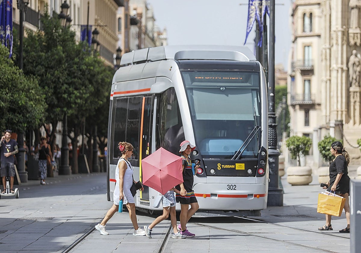 Un grupo de peatones cruza por delante del tranvía en la Avenida de la Constitución
