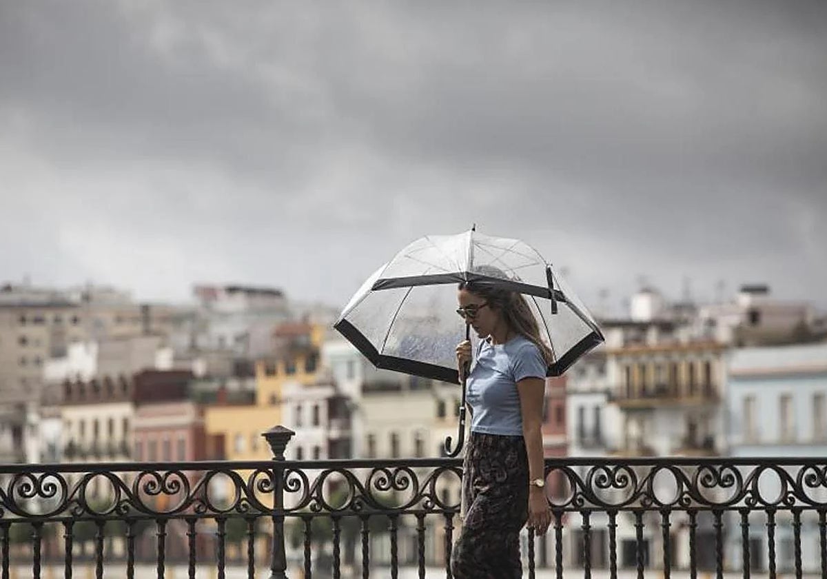 Una mujer cruza el puente de Triana en un día lluvioso en imagen de archivo