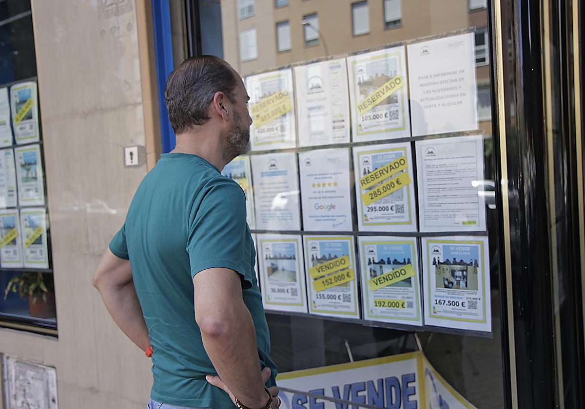 Una persona observa el escaparate de una agencia inmobiliaria