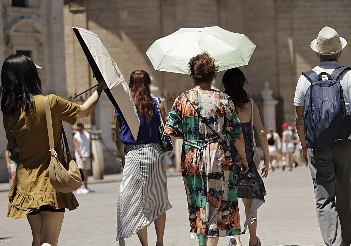 Turistas con paraguas por calor excesivo en Sevilla