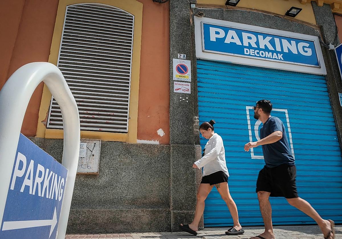 Dos personas caminan junto al aparcamiento de Muñoz León en Sevilla
