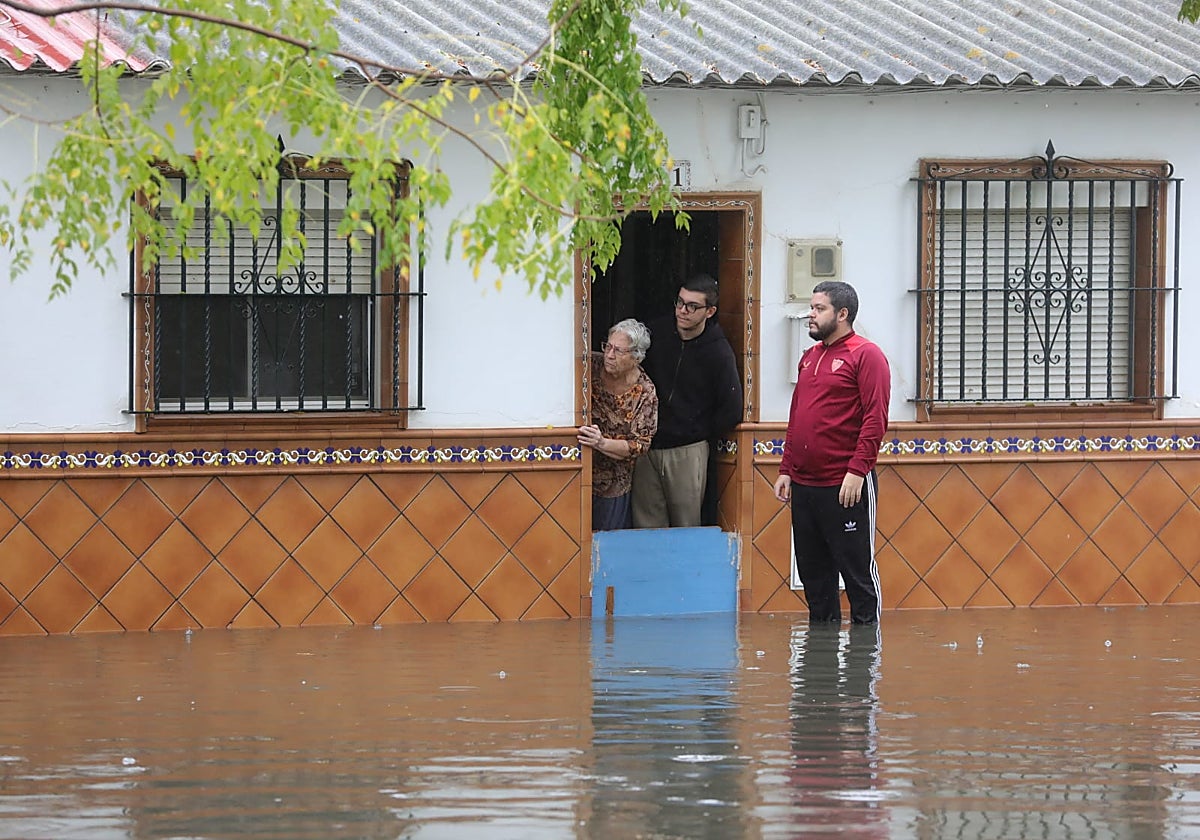 Vecinos de un barrio de Sevilla protegen la entrada de su casa frente a las inundaciones provocadas por las fuertes lluvias