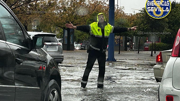 Un agente organiza el tráfico con el agua muy por encima de sus pies