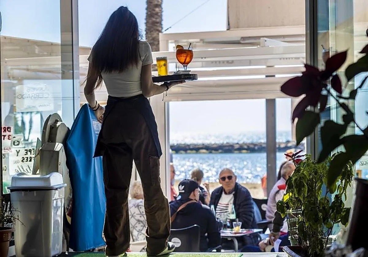 Una camarera atiende una terraza en un chiringuito en la costa