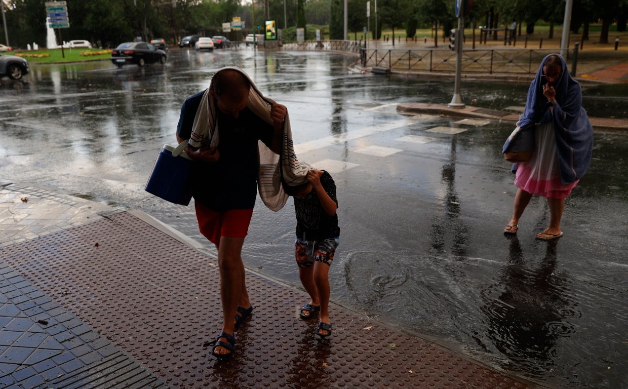 Personas se protegen de la lluvia en Madrid tras una tormenta sucedida a principios de agosto de 2022