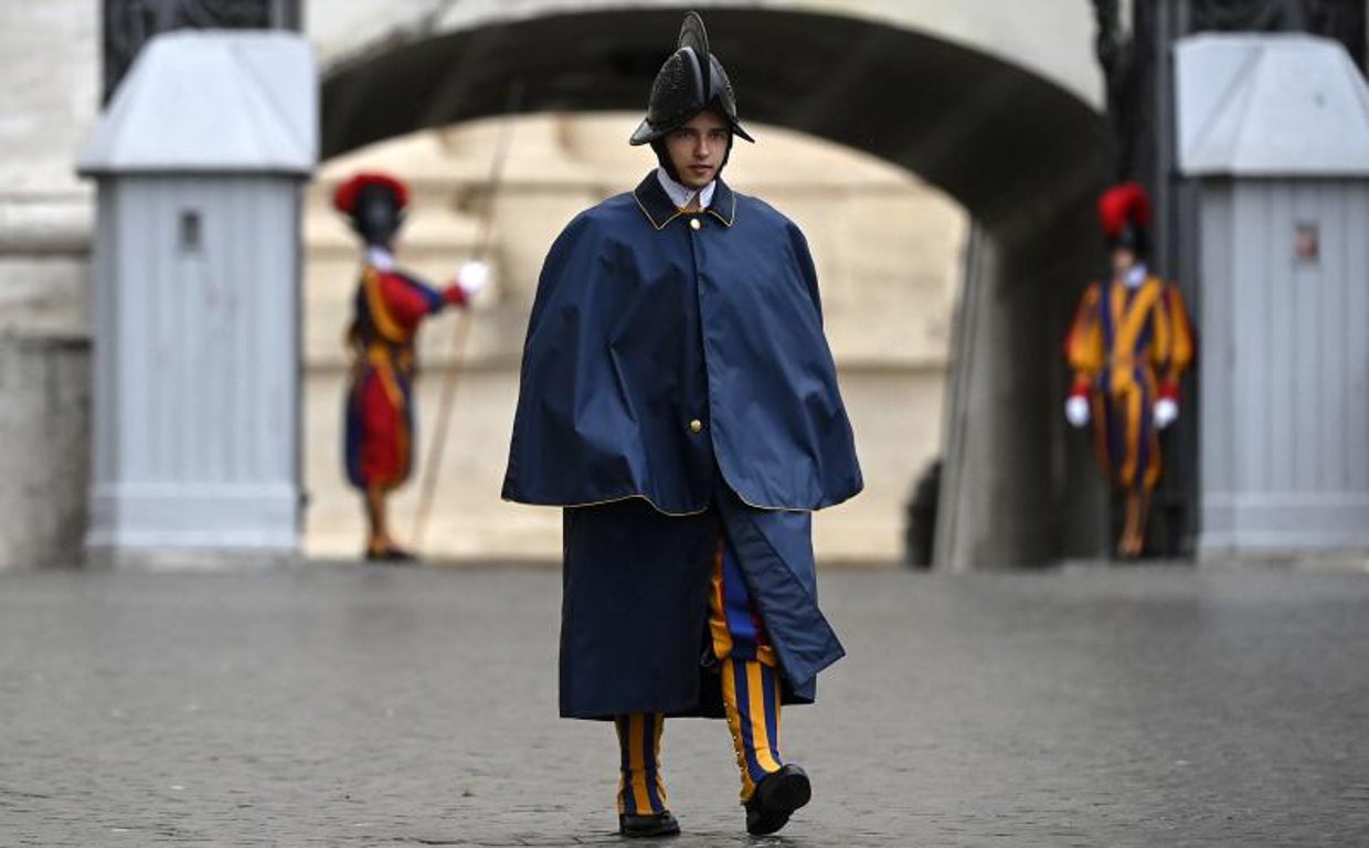 Un guardia suizo, con capote para la lluvia, protege una de las entradas del Vaticano