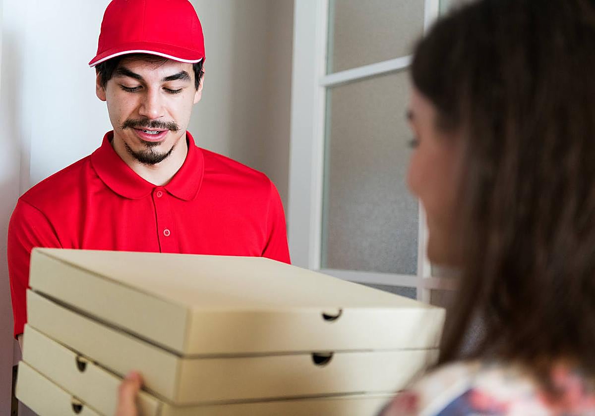 Imagen de archivo de un repartidor de pizza con un cliente