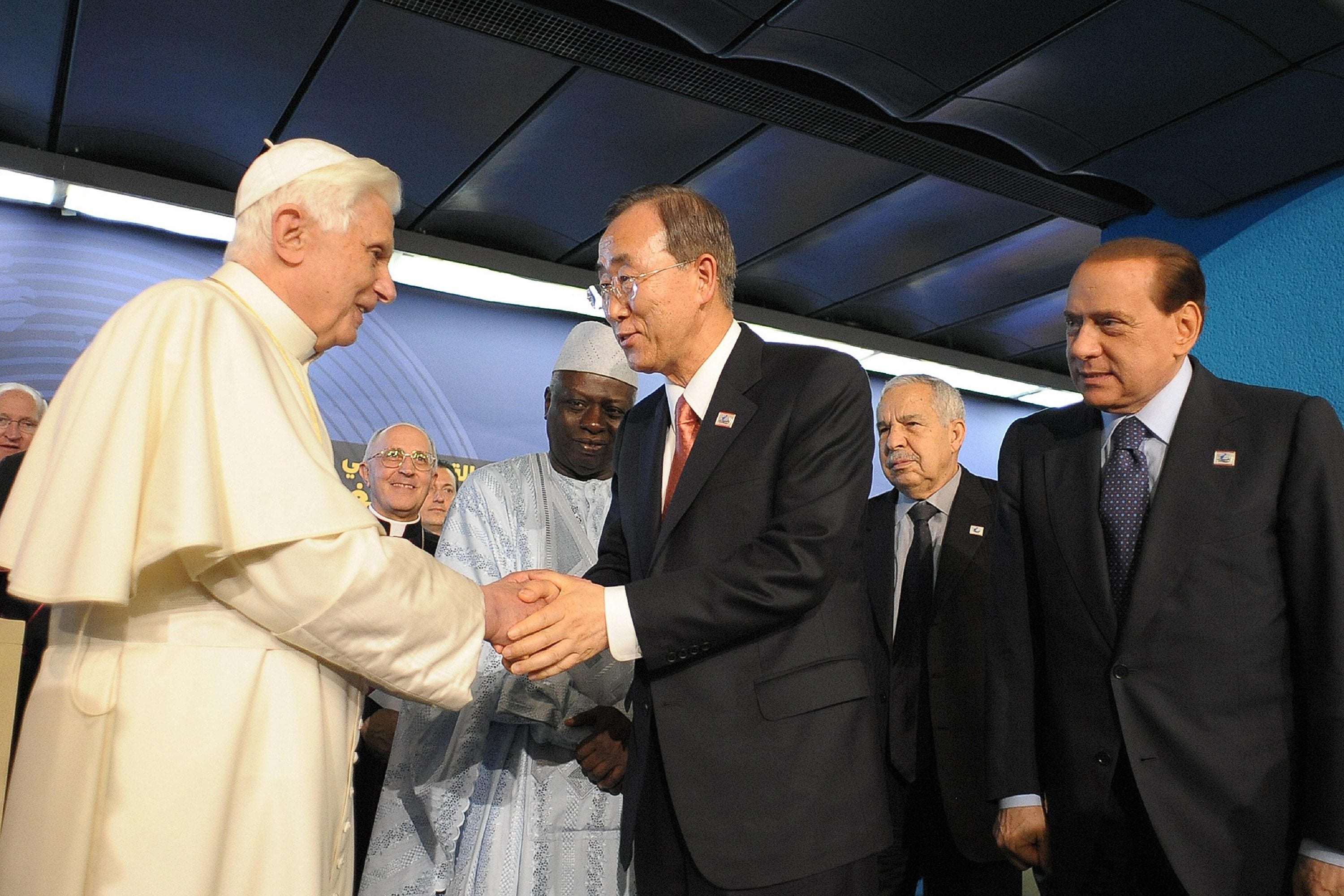 Benedicto XVI saluda al Secretario General de la ONU, Ban Ki-moon, junto a Silvio Berlusconi, en la ceremonia de apertura de la Cumbre Mundial sobre Seguridad Alimentaria el 16 de noviembre de 2009.