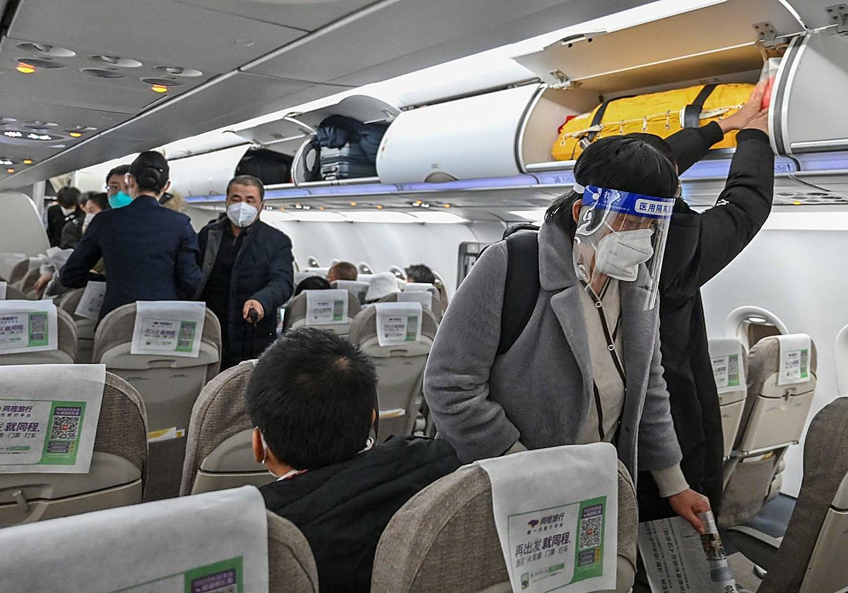 Personas con mascarilla y pantalla protectora en un vuelo que sale desde Shangái