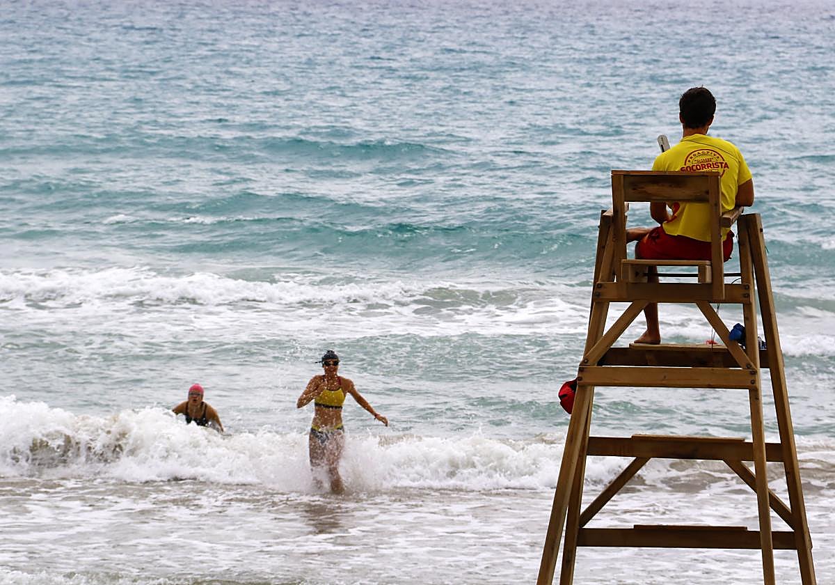 Imagen de archivo de un socorrista y dos bañistas en una playa