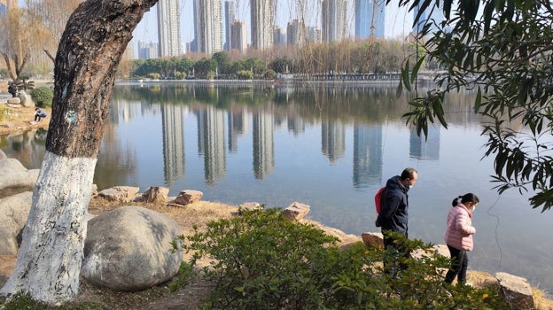 Una familia pasea por un parque en el centro de Wuhan