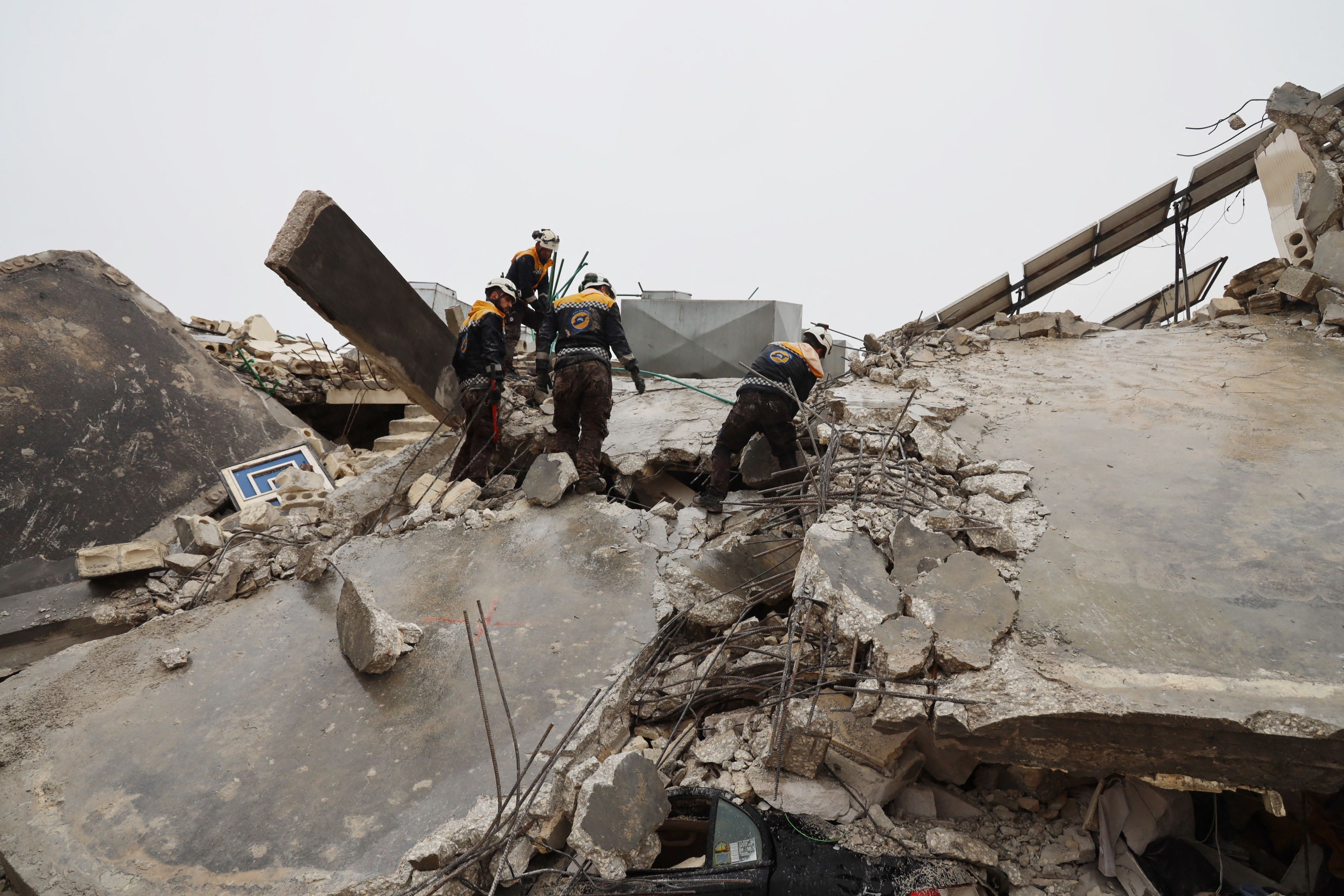 Miembros de la defensa civil siria, conocidos como los Cascos Blancos, buscan víctimas bajo los escombros tras el terremoto en la ciudad de Sarmada