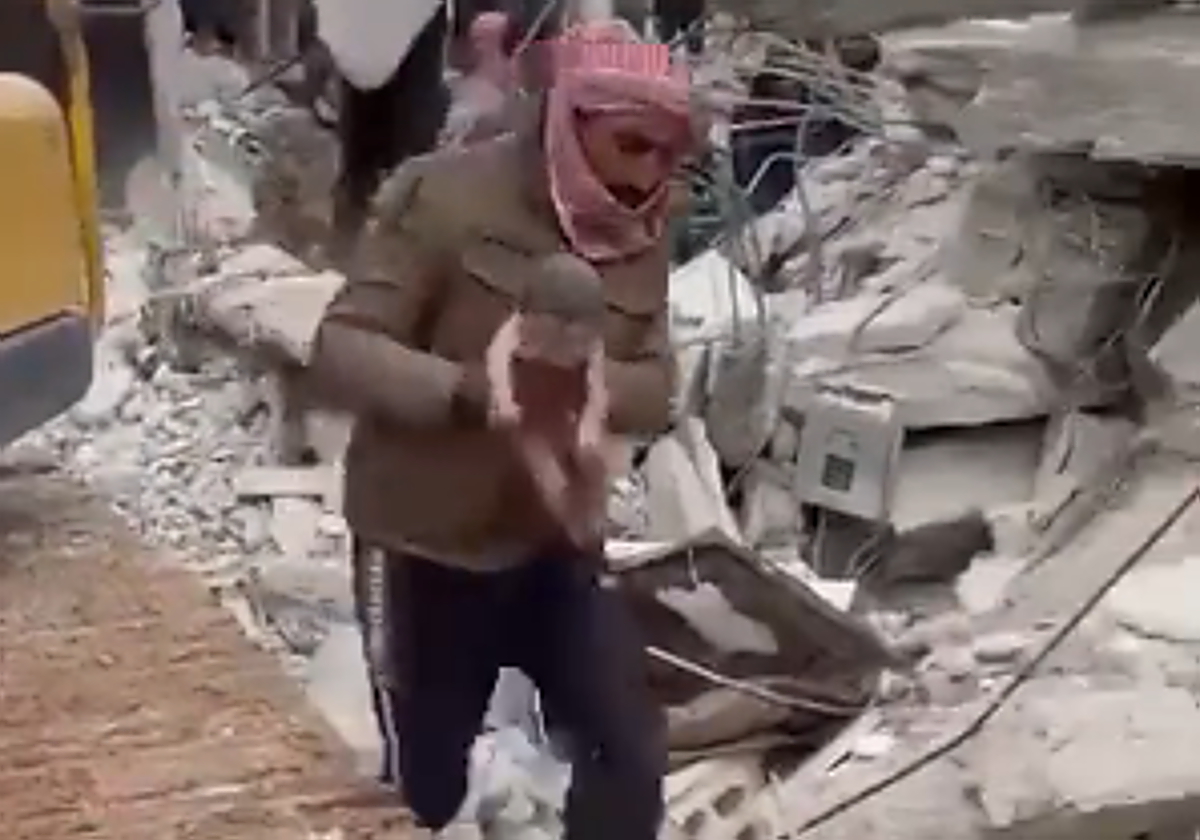 Un hombre sale de las ruinas con un bebé recién nacido en brazos