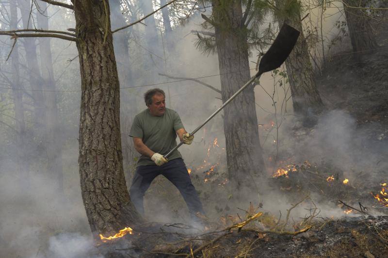 Un hombre trabaja en las labores de extinción del incendio declarado en Navelgas, Asturias