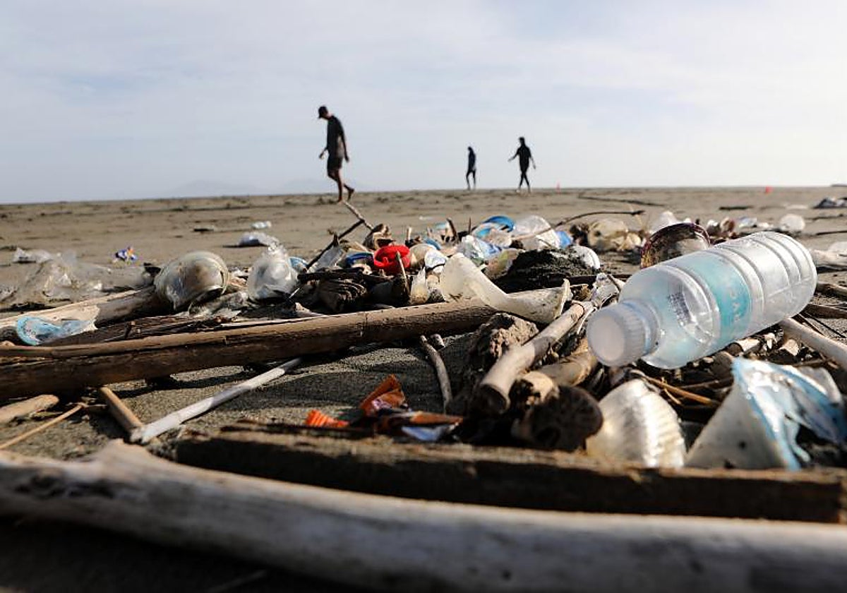 La gente pasea por una playa llena de residuos plásticos
