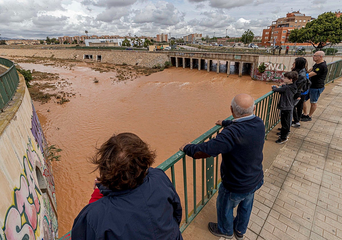 Varias personas observan la rambla de Benipila de Cartagena tras las fuertes lluvias