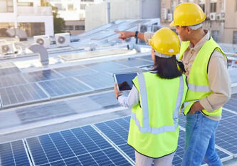 Dos trabajadores frente a unos paneles solares