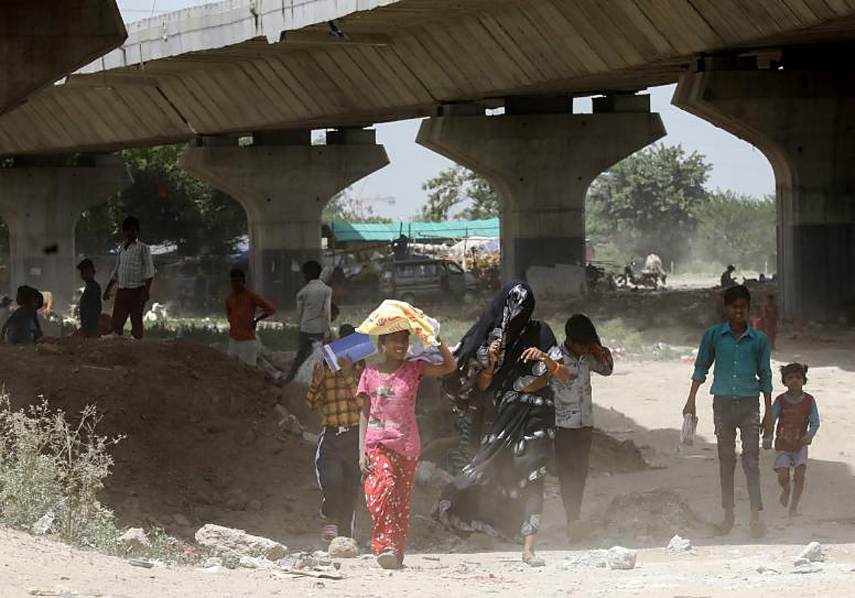 Personas intentando protegerse del calor mientras caminan por el cauce del río Yamuna (Nueva Delhi)