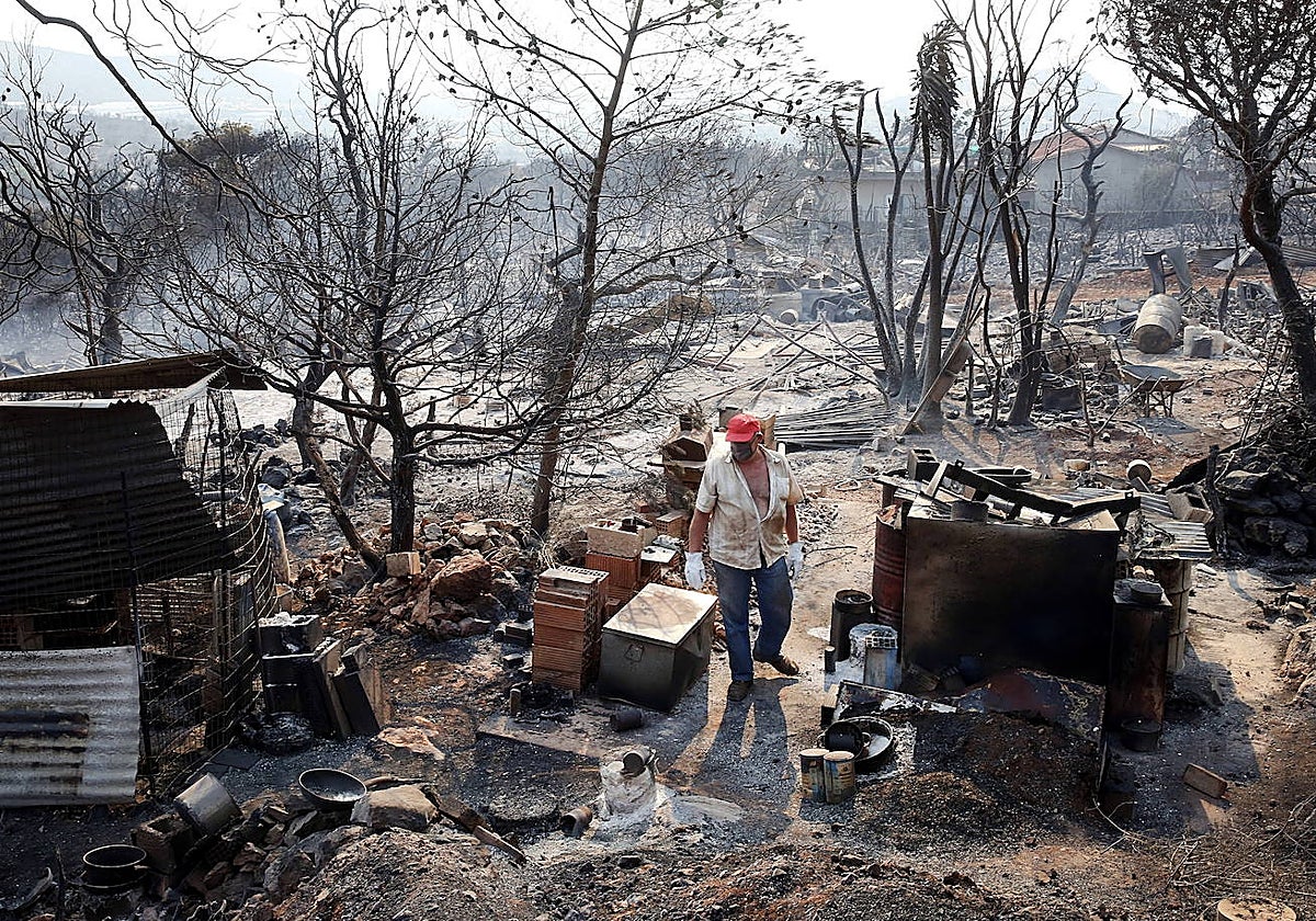 Un residente inspecciona los daños en su propiedad debido a un incendio forestal en la región de Attica, Grecia