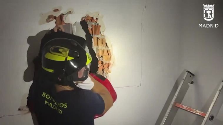 Bomberos de Madrid realizan un butrón en la pared para rescatar a 3 personas