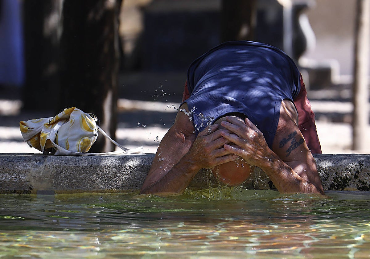 Un turista se refresca  en la Fuente de los Naranjos de la mezquita-catedral de Córdoba