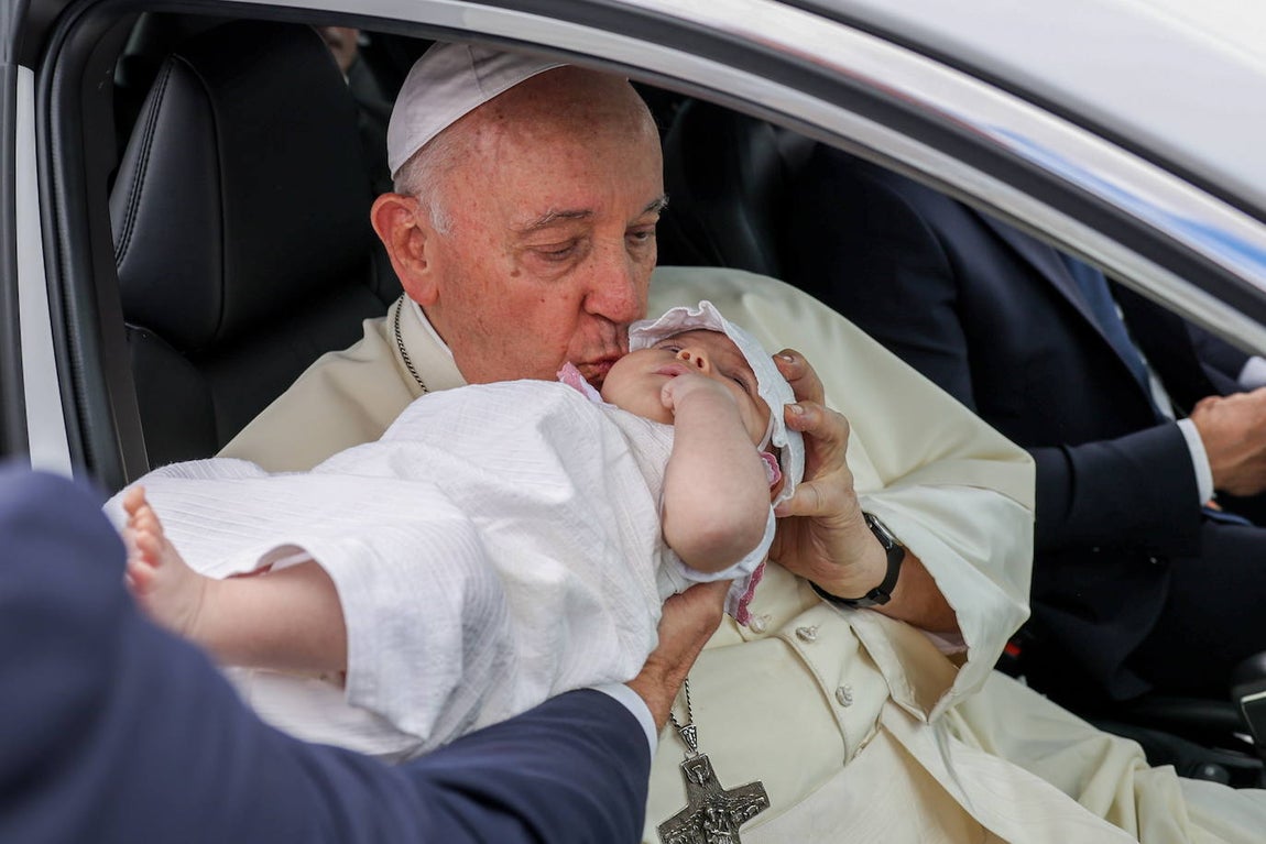 El Papa Francisco besa a un bebé en la mejilla durante el trayecto entre el Palacio de Belém y el Centro Cultural de Belém tras un encuentro con el presidente de Portugal