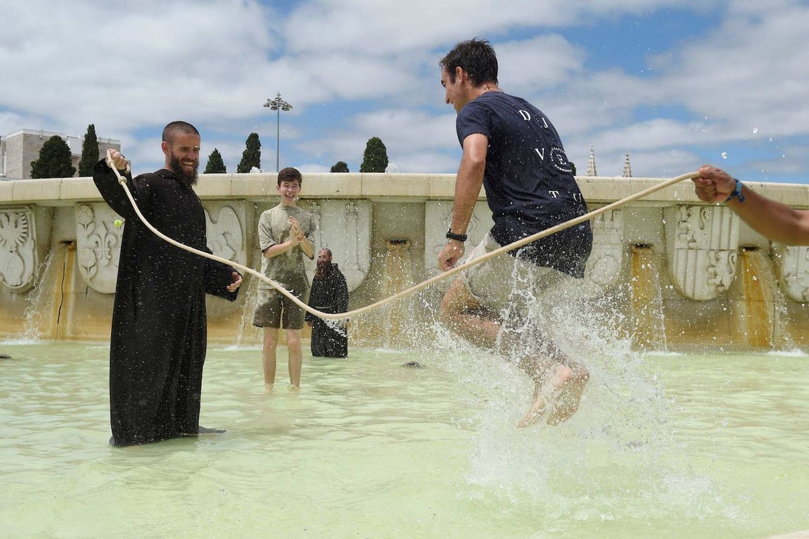 Un sacerdote y peregrinos se refrescan en una fuente, mientras esperan al Papa cerca del Monasterio de los Jerónimos