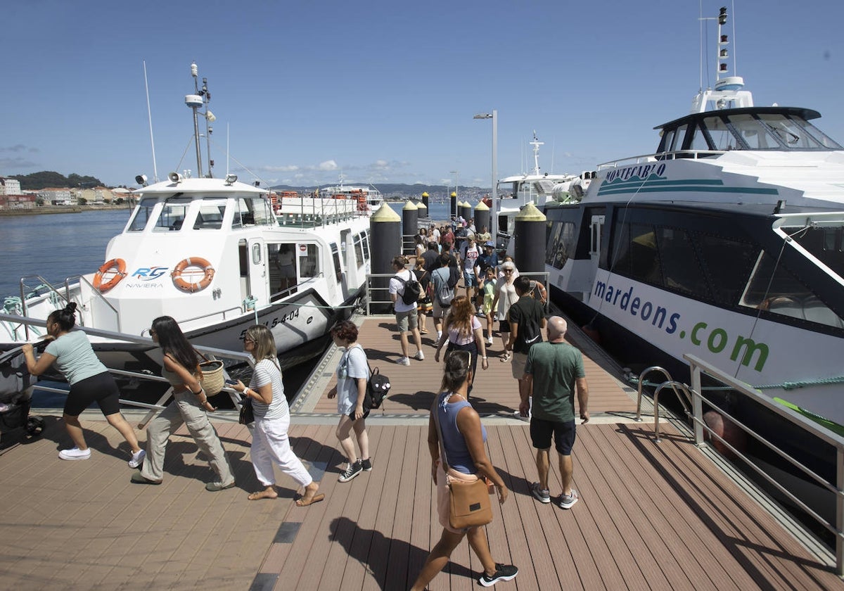Turistas recorren la pasarela en la que atracan los barcos a las Islas Cíes