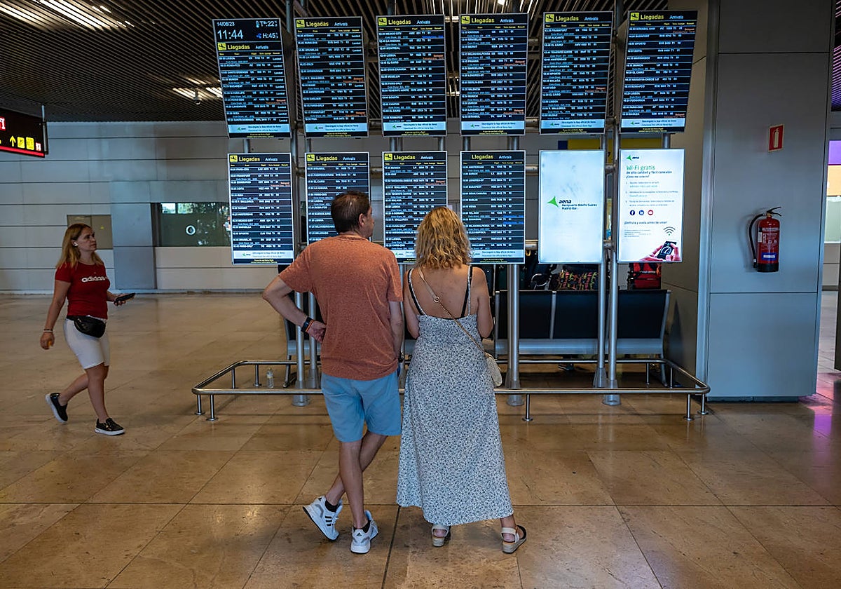Dos personas revisan el panel de llegadas en el aeropuerto internacional de Adolfo Suárez Madrid Barajas