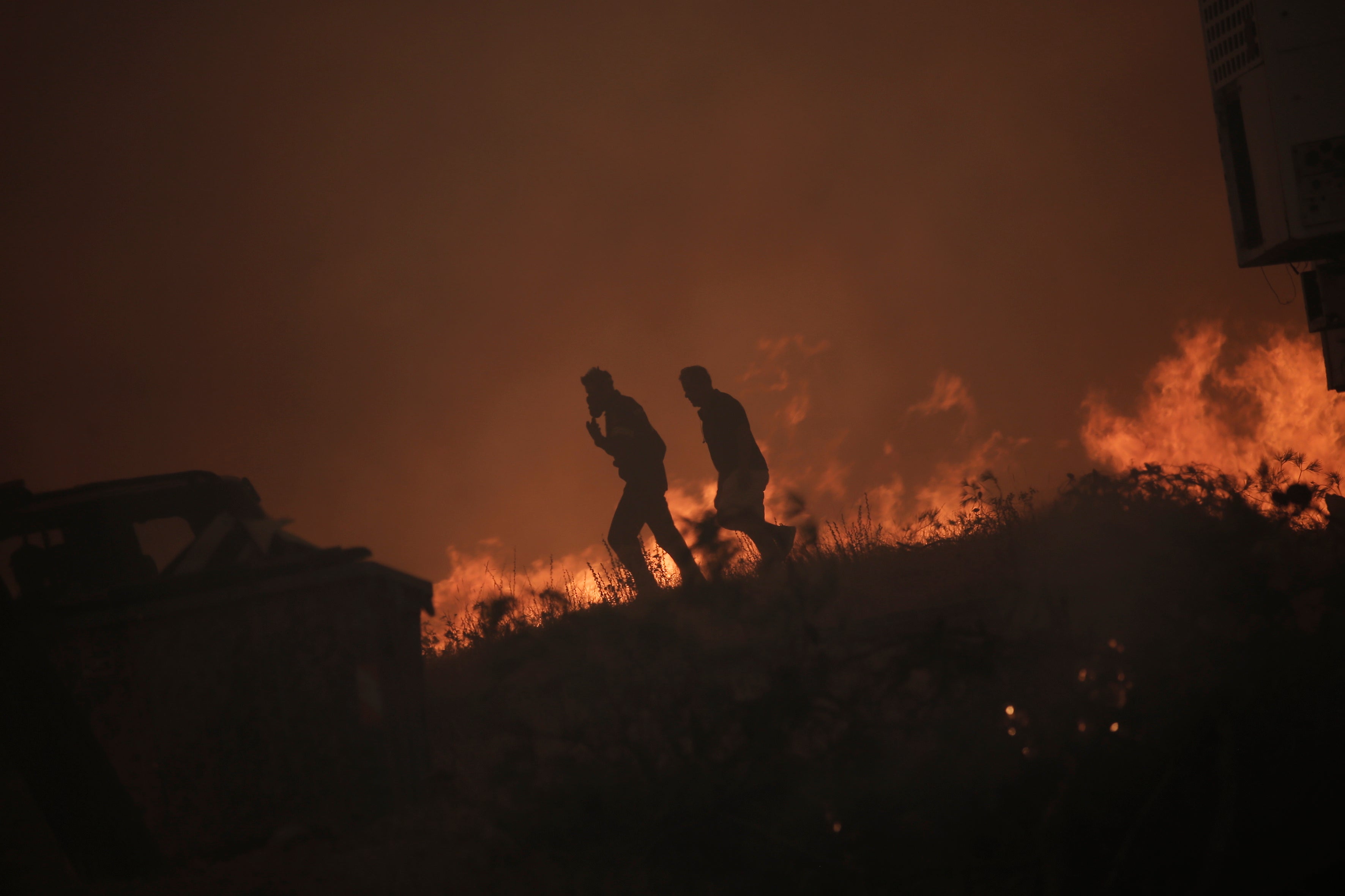 Un bombero y un residente local se alejan de las llamas durante el incendio en la zona de Fyli, cerca de Atenas 